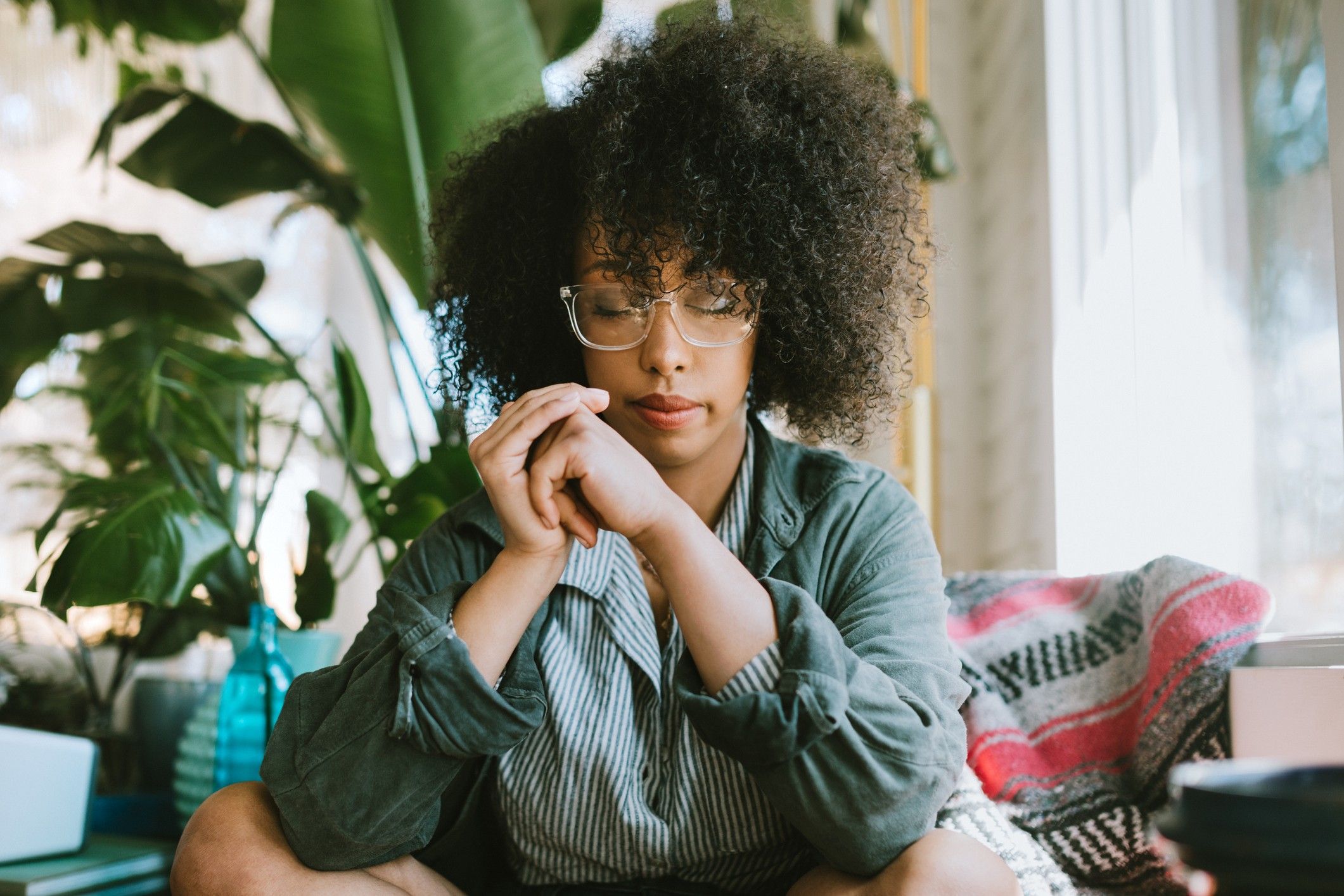 Woman-wearing-glasses-sitting-cross-legged-meditating-resting-her-eyes