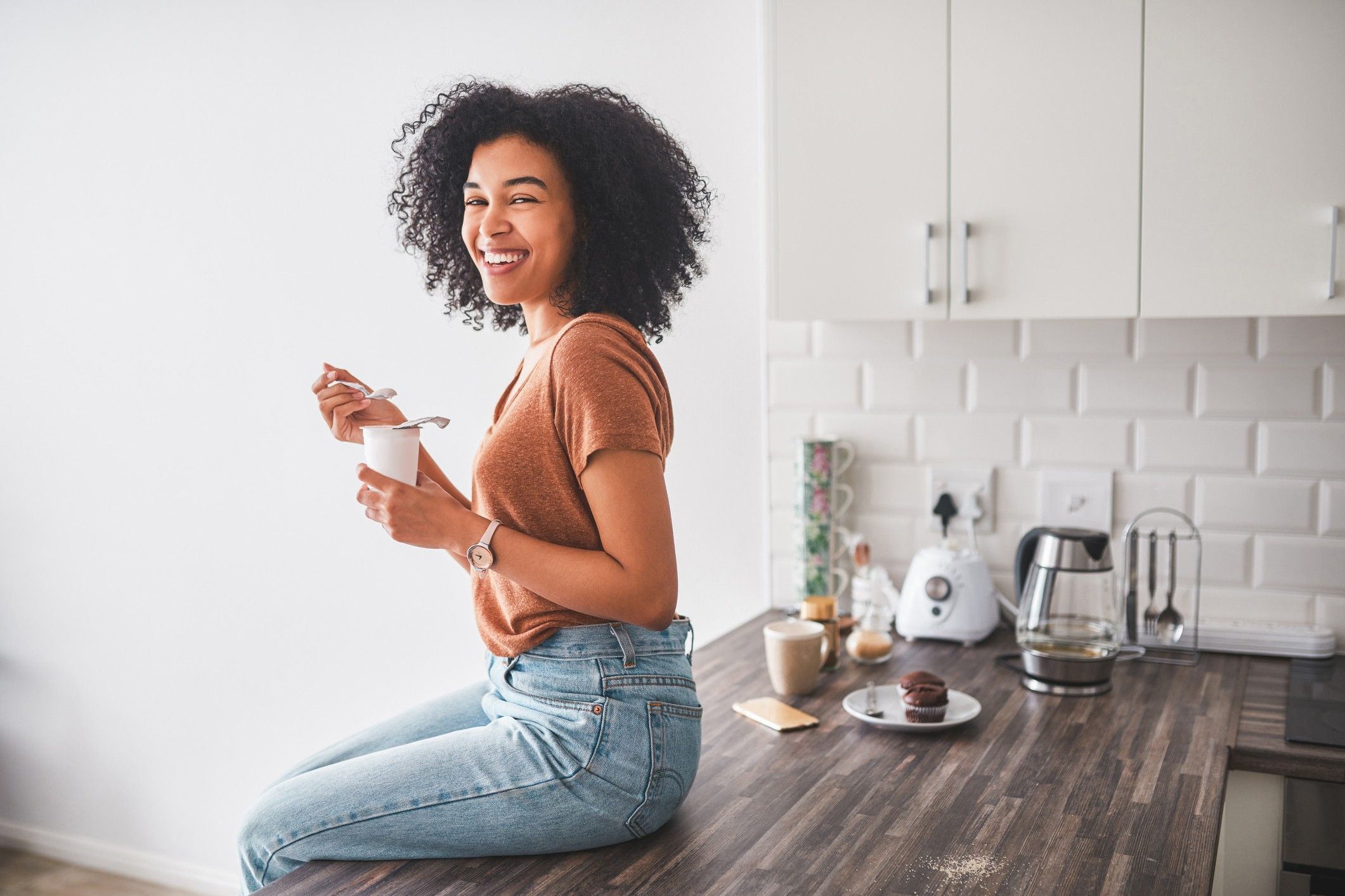 black-woman-smiling-eating-yogurt-sitting-on-kitchen-table