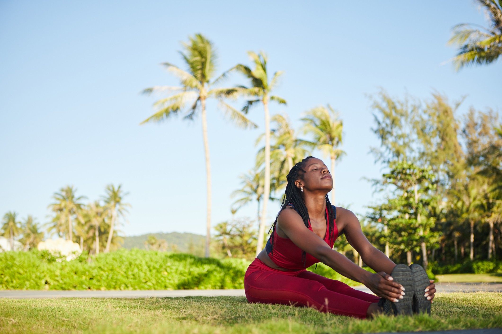 Happy-woman-sitting-on-ground-legs-straight-and-together-holding-her-feet-in-a-stretch
