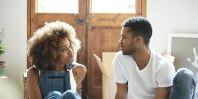 Couple-talking-intently-together-as-they-sit-on-the-floor-and-enjoy-beers