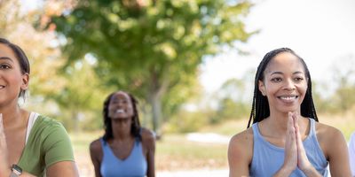 Black-women-posing-with-hand-over-heart-during-an-outdoor-yoga-class