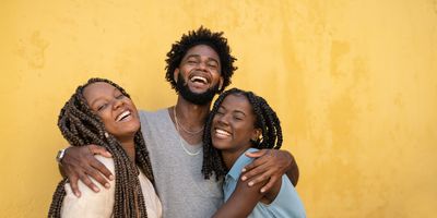 hugging-friendship-group-laughing-against-yellow-wall