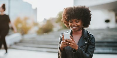 Smiling-Black-woman-texting-while-out-in-the-city