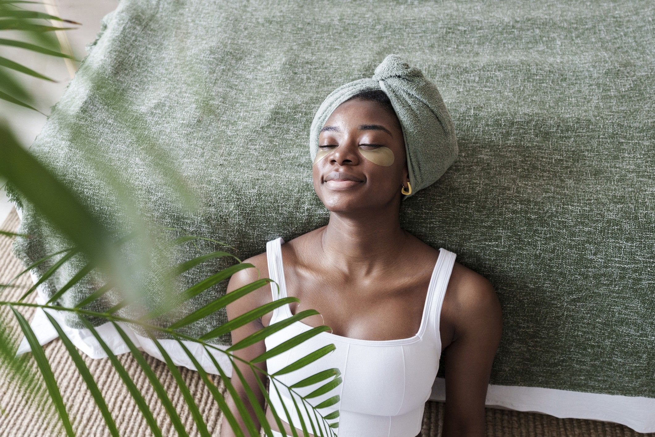 Black-woman-doing-skincare-treatment-at-home-leaning-against-bed