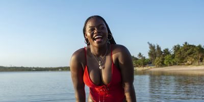 Black-woman-laughing-in-the-water-at-the-beach-in-swimsuit