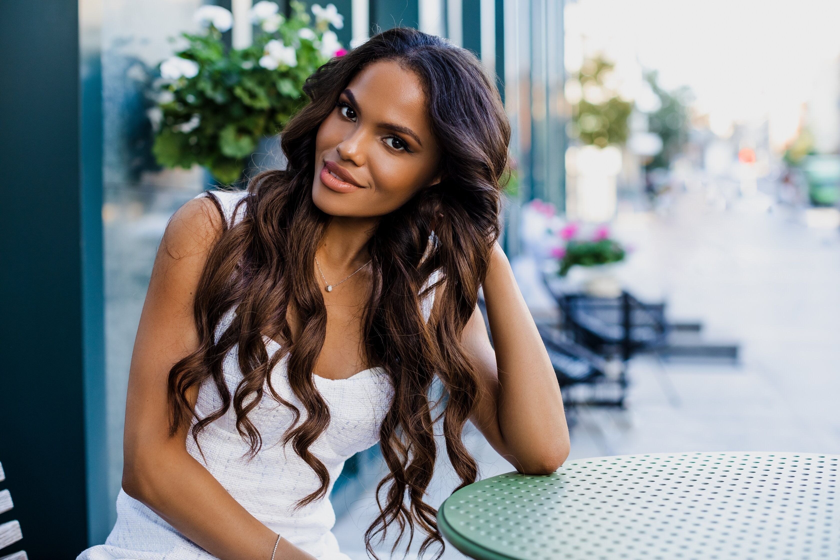 Beautiful portrait of an American girl with long curly hair sitting on a flyer in a cafe. woman smiling outdoors   