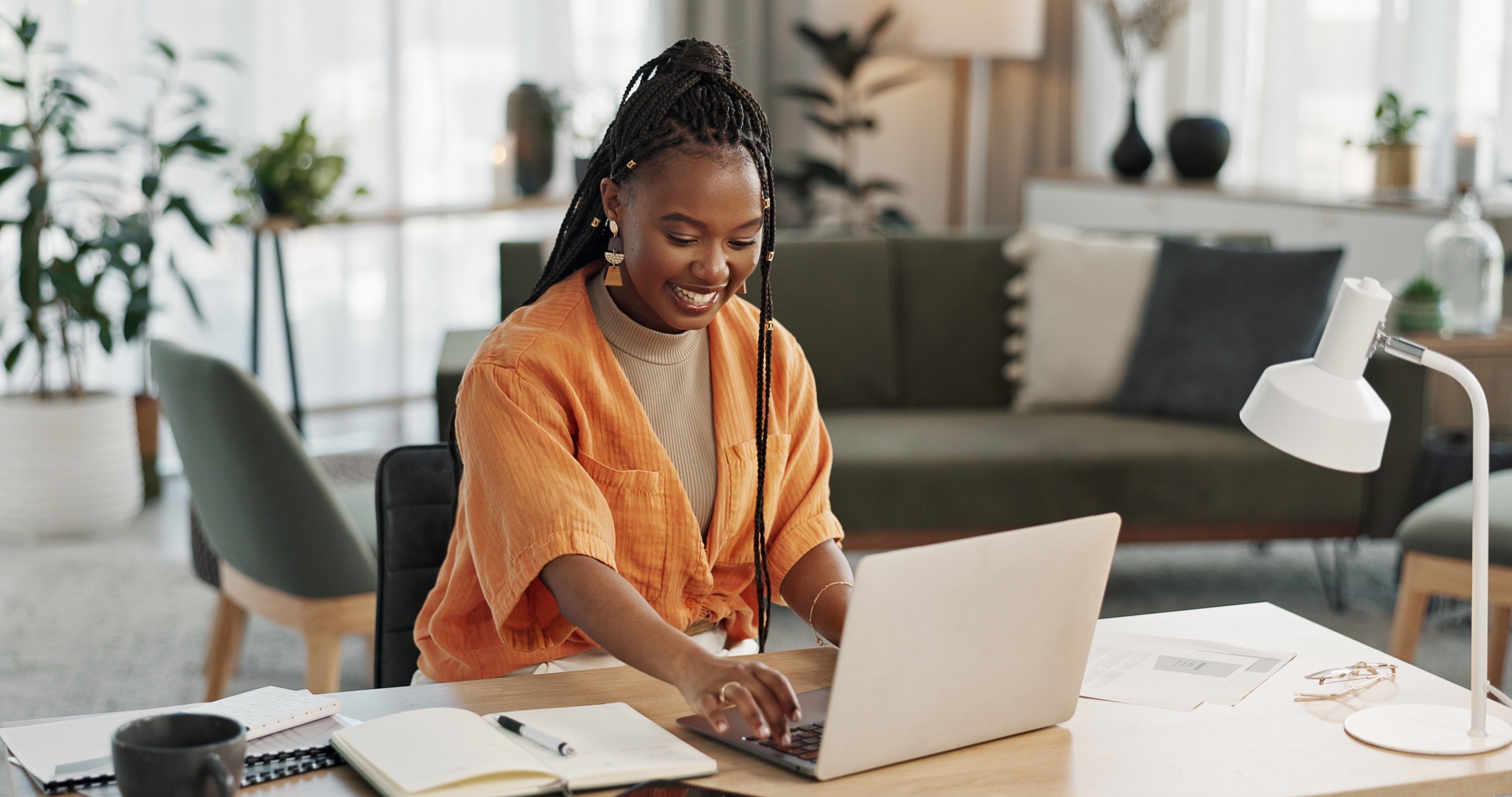 Black woman, typing in home office and laptop for research in remote work, social media or blog in apartment. Freelance girl at desk with computer writing email, website post and online chat in house
