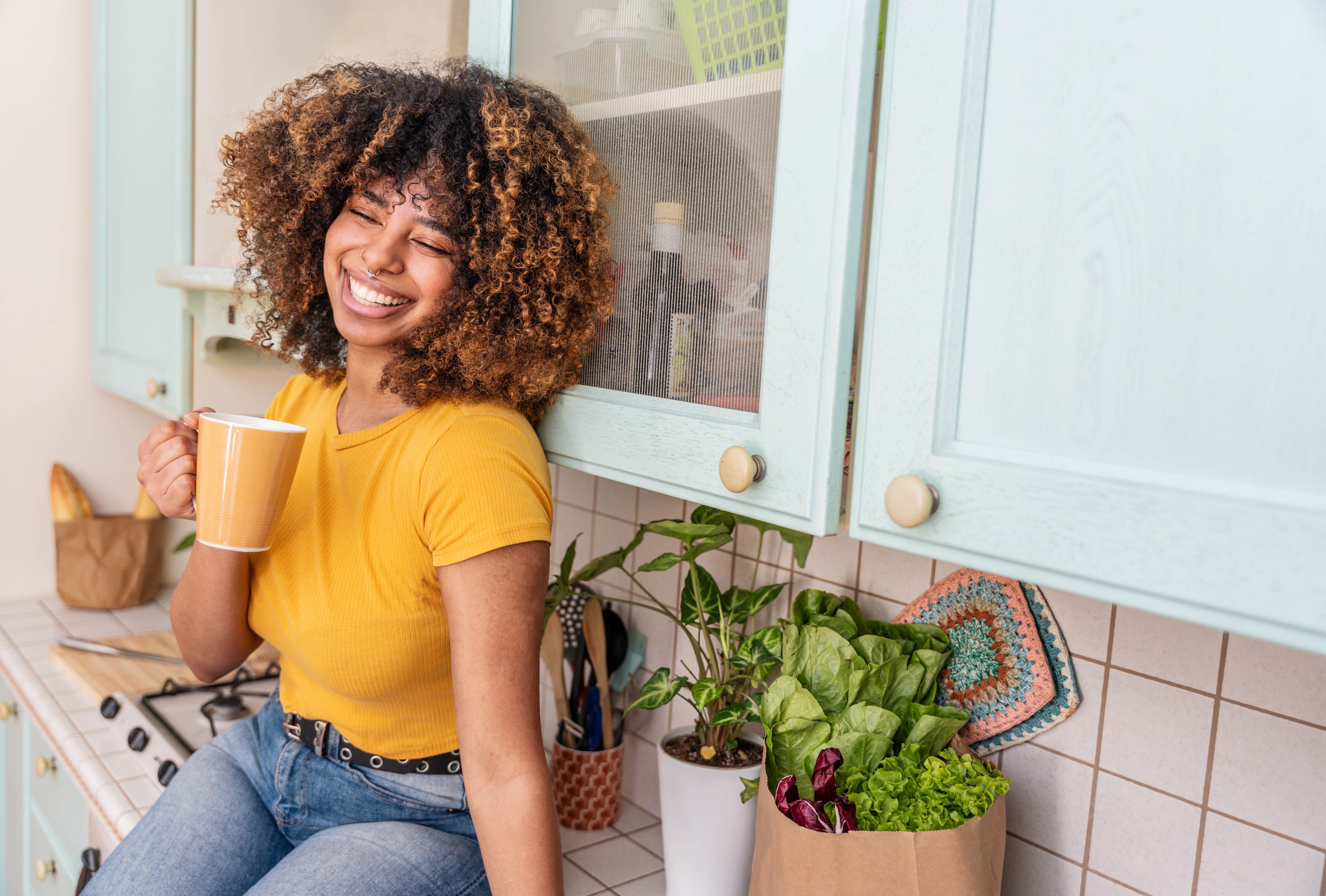 Happy black woman relaxing at home - Delightful female drinking waking up in the morning drinking tea