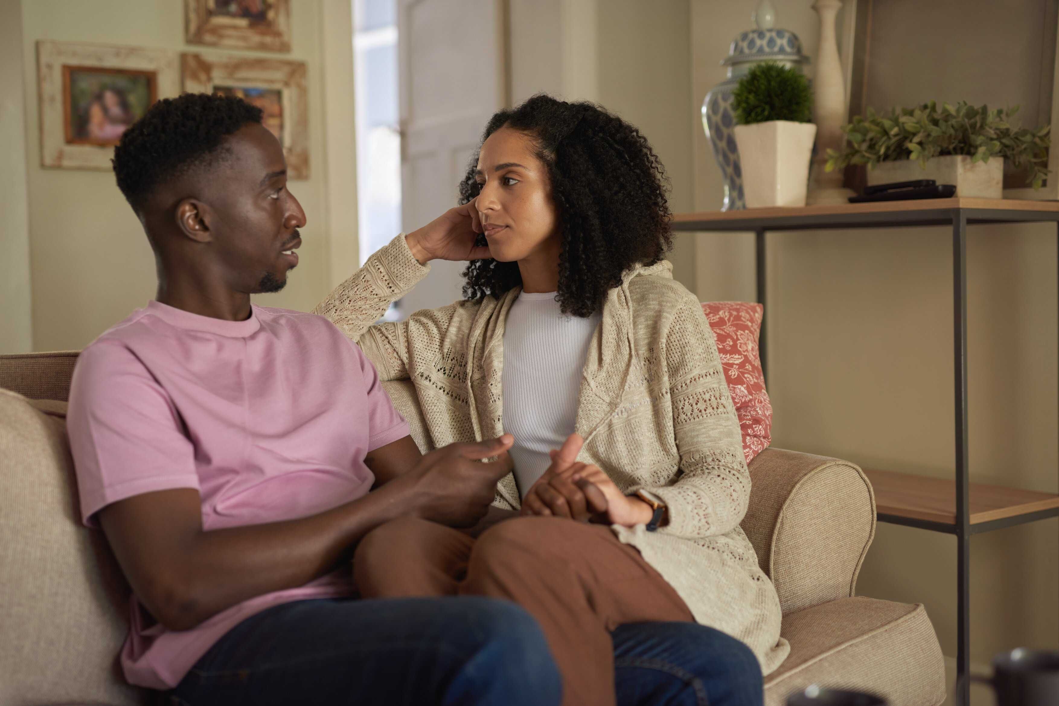 Young multiracial couple having an intimate conversation on their living room sofa, emotional connection and healthy communication