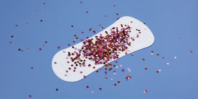 A-white-menstrual-pad-with-colorful-confetti-against-blue-background