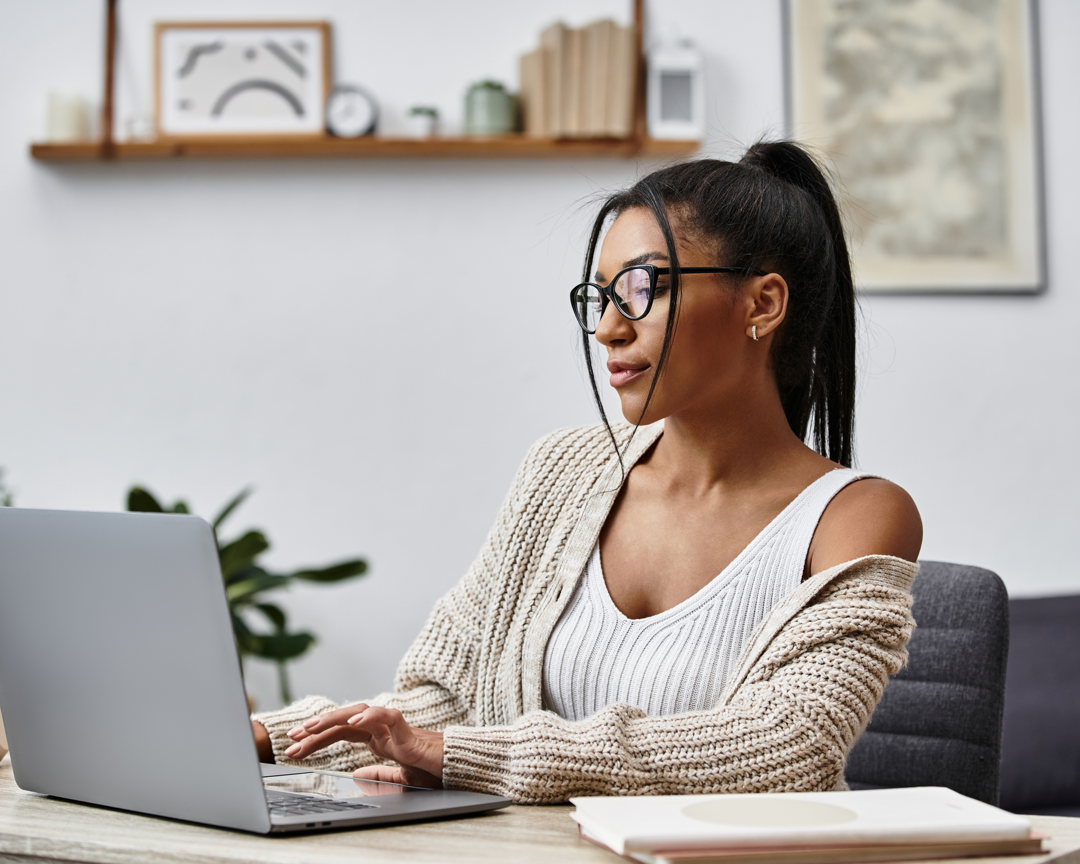 A beautiful young woman is engaged in remote learning, tapping away on her laptop at home.