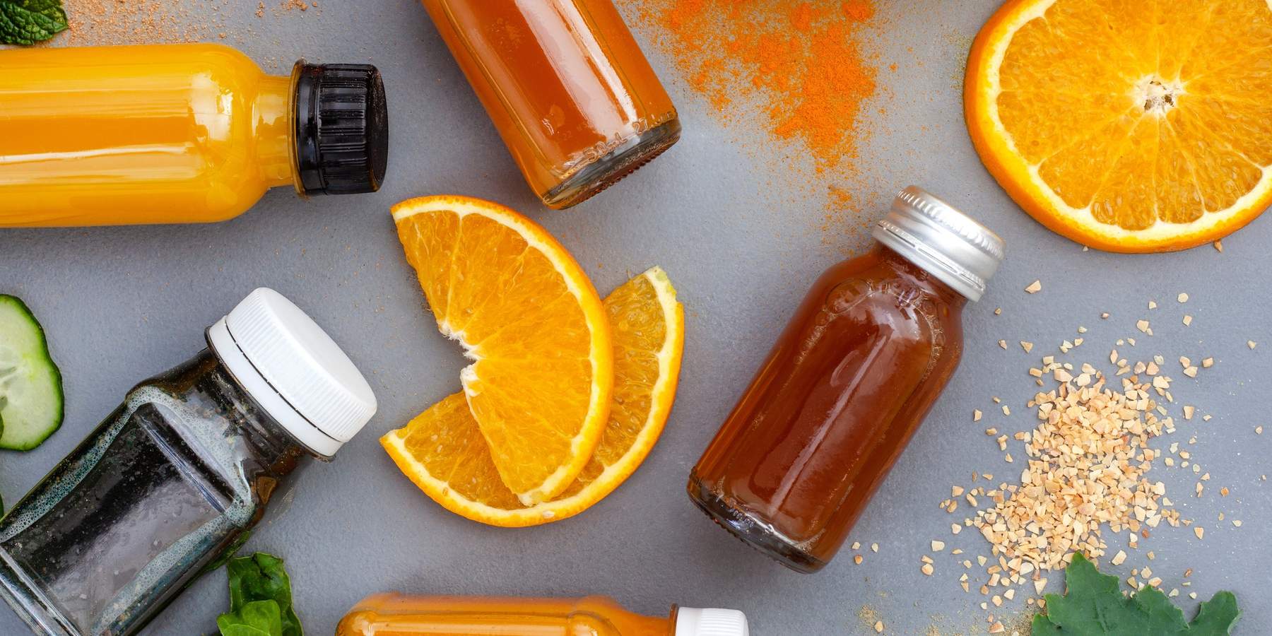 Juice shots for a healthy lifestyle, flat lay on dark grey with ingredients