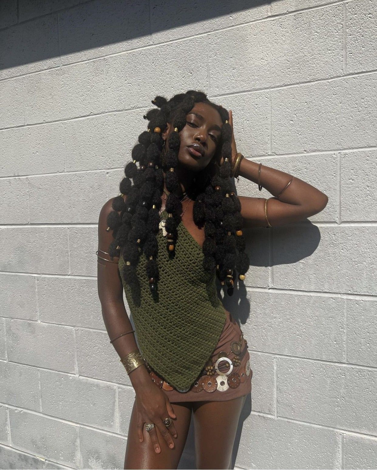 woman-wearing-bubble-braids-poodle-puffs-hairstyle-posing-against-white-brick-wall