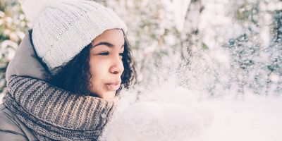 woman-in-a-winter-wonderland-blowing-snow-from-her-hands-in-playful-way