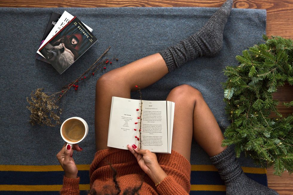 opened-book-on-person-s-lap-with-gray-socks-holiday-garland-decoration