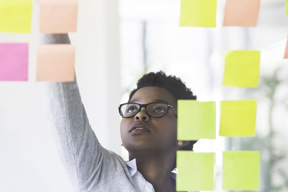 pensive-young-woman-arranging-sticky-notes-on-her-vision-board