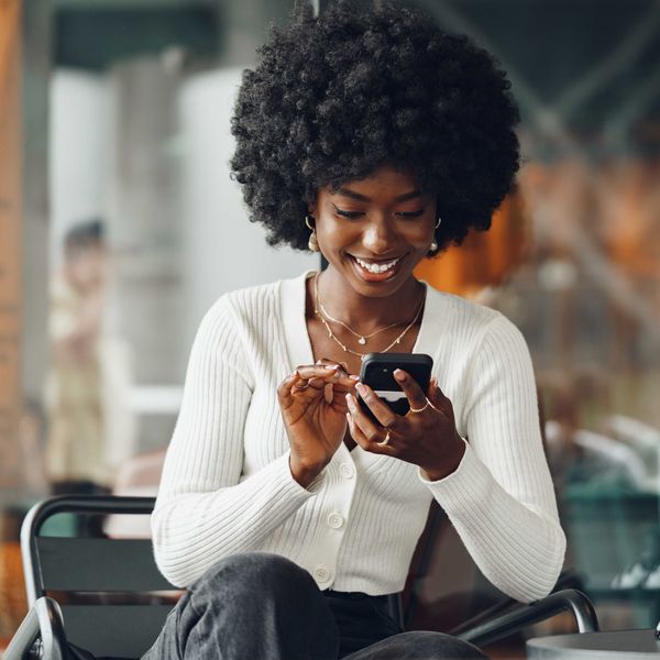 Portrait of a beautiful young african woman using her cellphone in a cafe