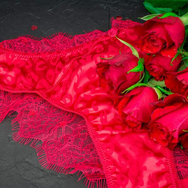 Red-lace-panties-and-bouquet-of-red-roses-against-black-background