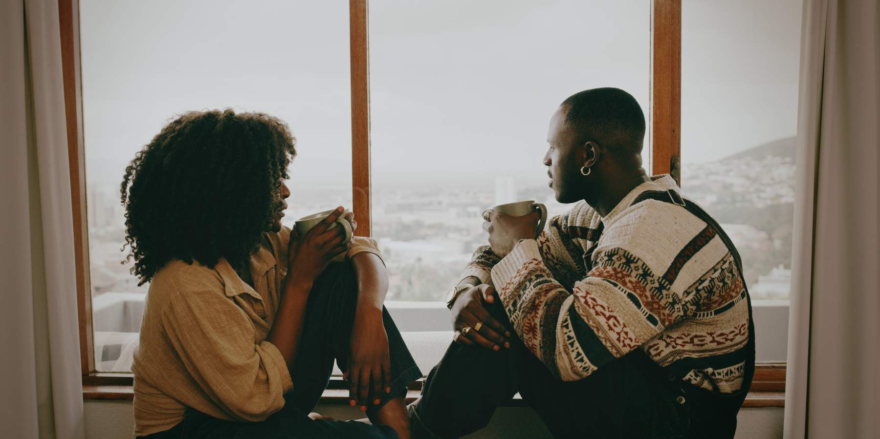 Shot-of-a-young-couple-talking-over-coffee-by-a-window