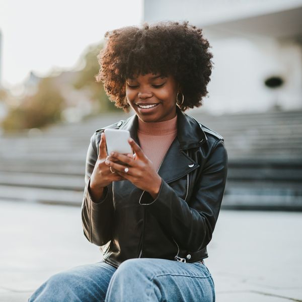 Smiling-Black-woman-texting-while-out-in-the-city