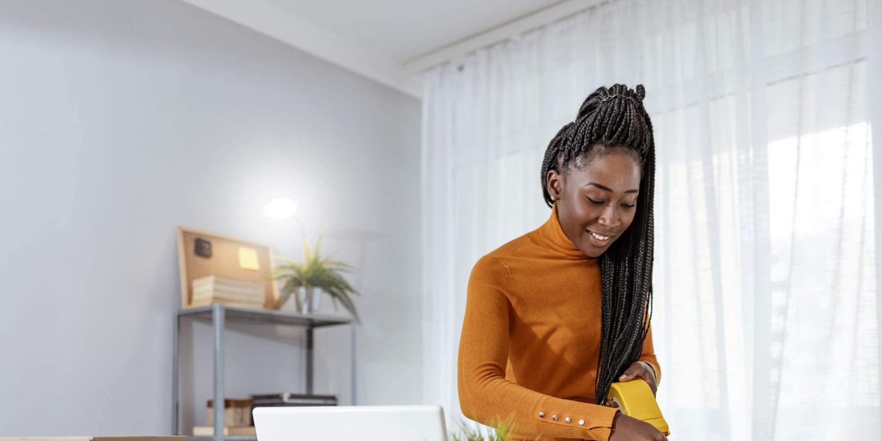 Smiling-Black-woman-with-braids-organizing-her-work-space