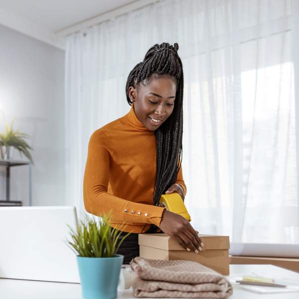 Smiling-Black-woman-with-braids-organizing-her-work-space