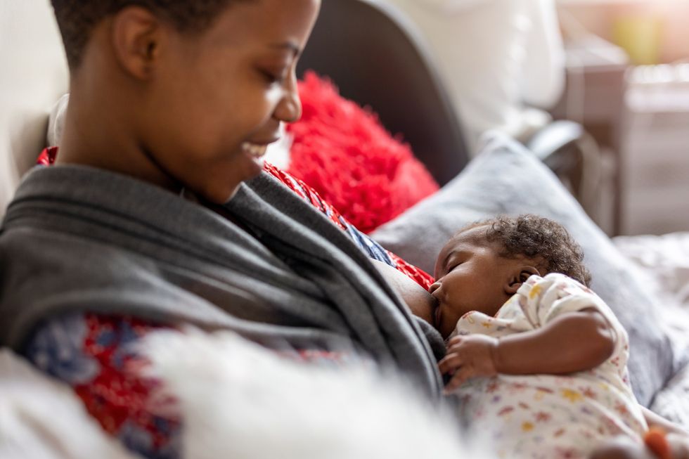 Smiling-woman-holding-her-child-as-she-breastfeeds