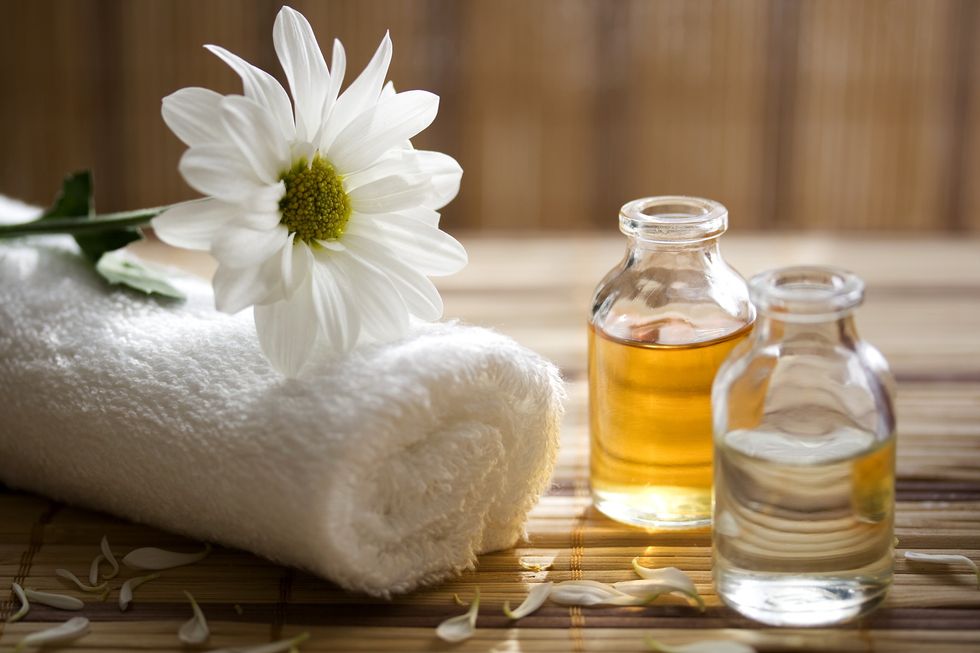 spa-setting-with-towel-a-white-flower-and-assorted-oils