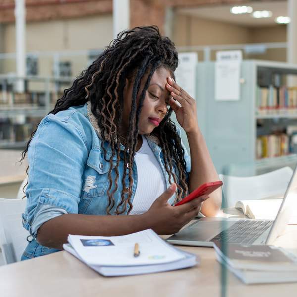 Stressed-Black-woman-checking-emails-on-laptop-and-phone