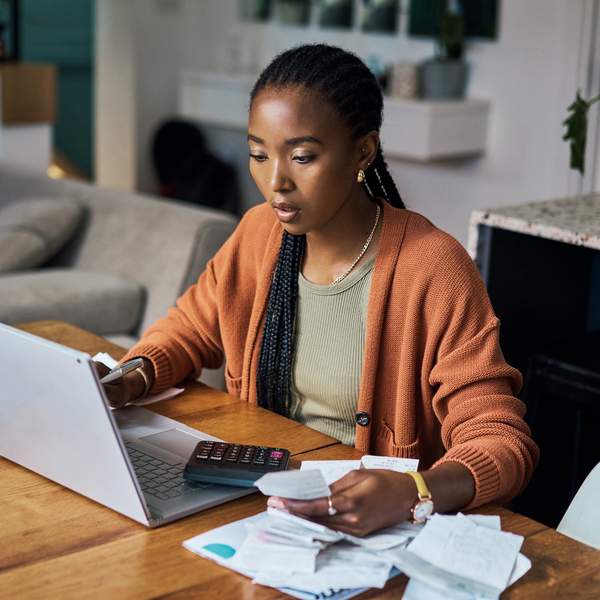 Stressed-woman-with-braids-calculating-expenses-from-assorted-reciepts