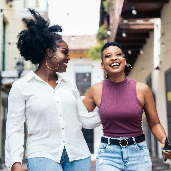 Stylish black women friends having fun and laughing a lot walking down the street