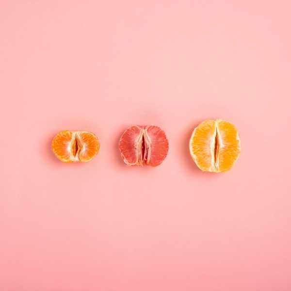 tangerine, grapefruit and orange cut in half on a peach background as a symbol of the vagina and female fertility, no people