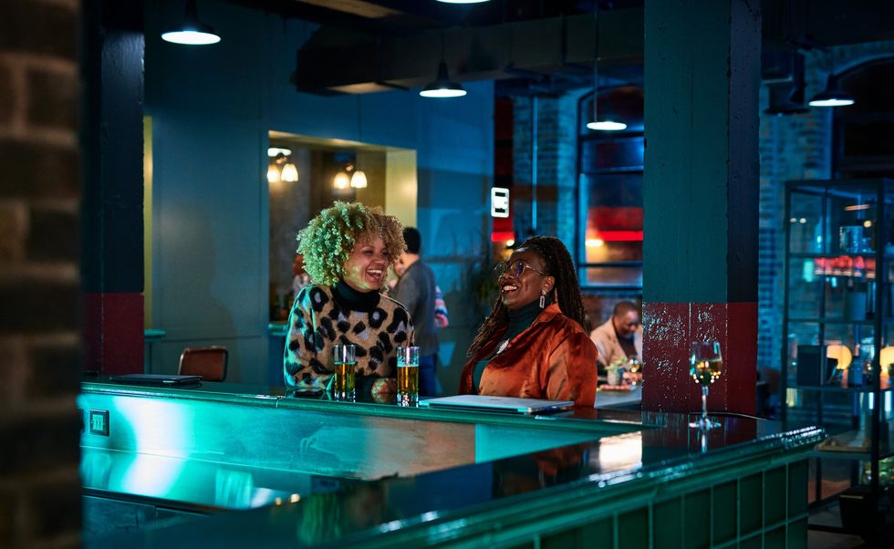 Two-friends-laughing-at-a-bar-over-beers-on-a-friend-date