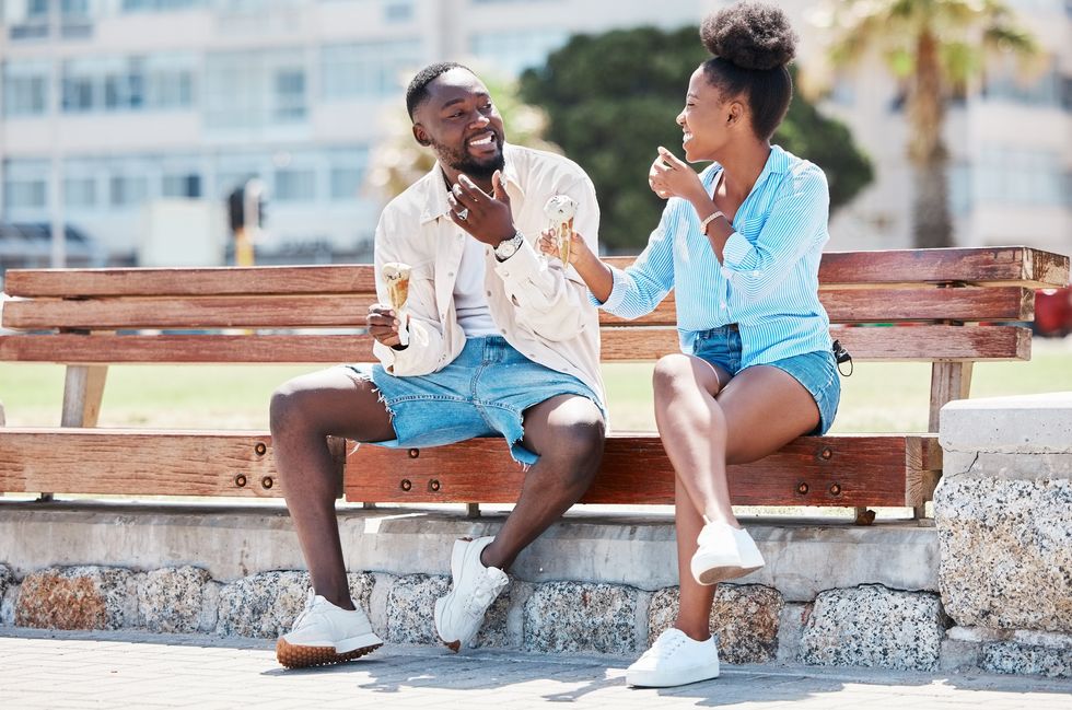 Two-friends-laughing-on-a-park-bench-eating-ice-cream-cones