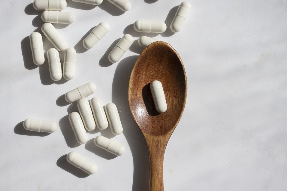 White-pills-on-a-white-backdrop-wooden-spoon