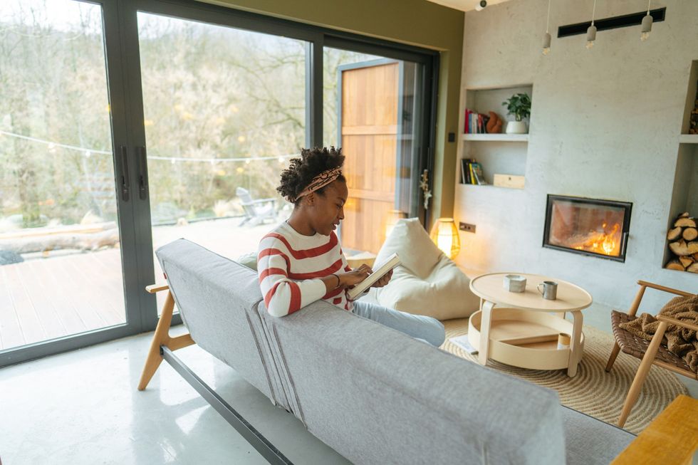 woman-reading-a-book-in-living-room-with-a-fire-burning-in-fireplace