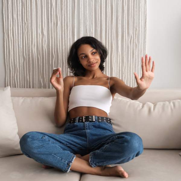 Woman sitting crossed-legged on a couch examining her nails for signs they need a break, nail care for healthy nails