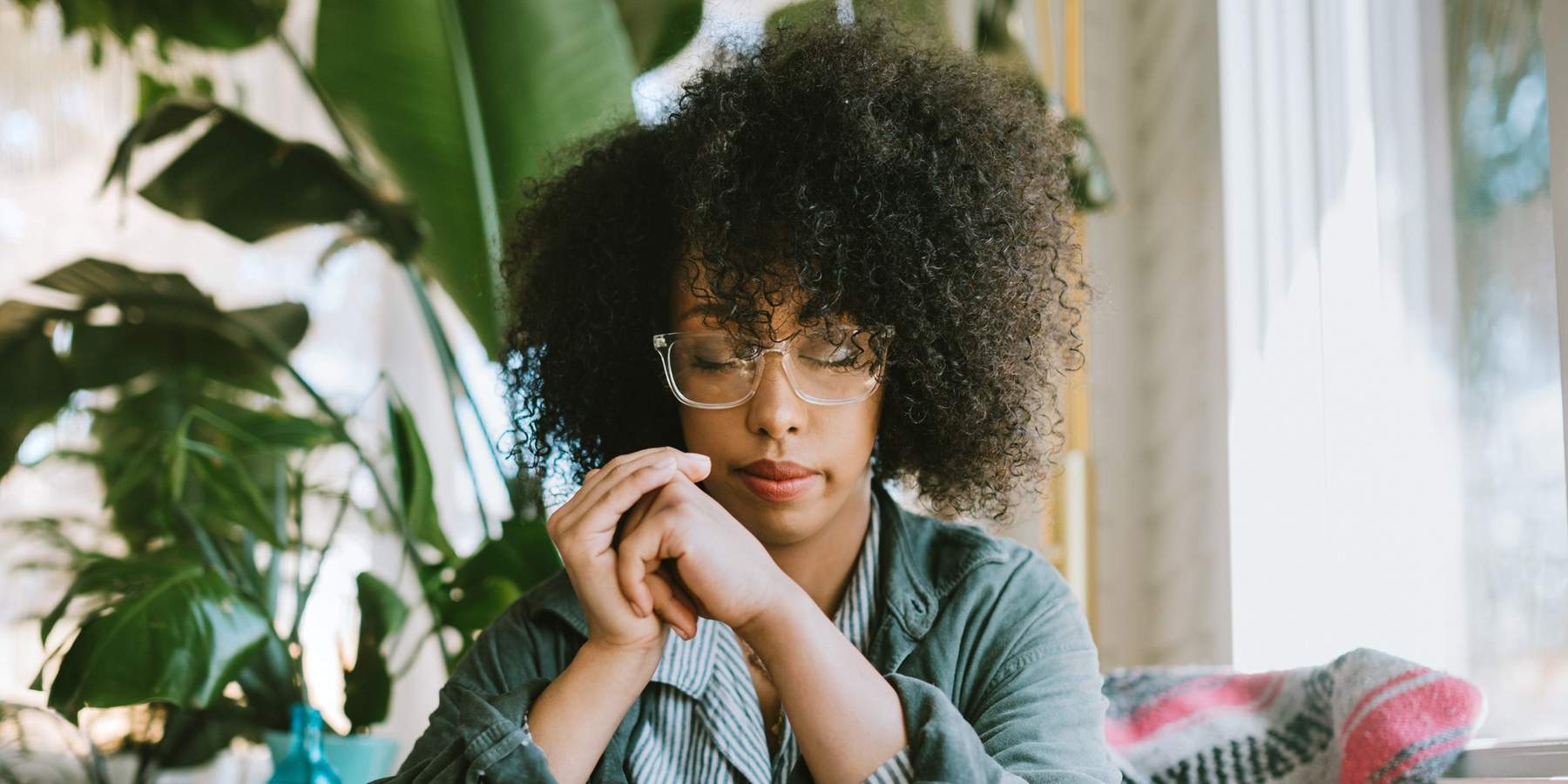 Woman-wearing-glasses-sitting-cross-legged-meditating-resting-her-eyes