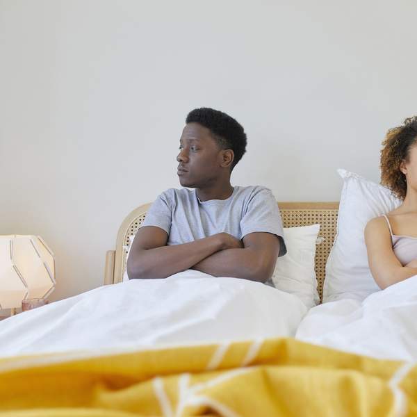 Young-couple-in-bed-next-to-each-other-looking-away-from-each-other-looking-irritated