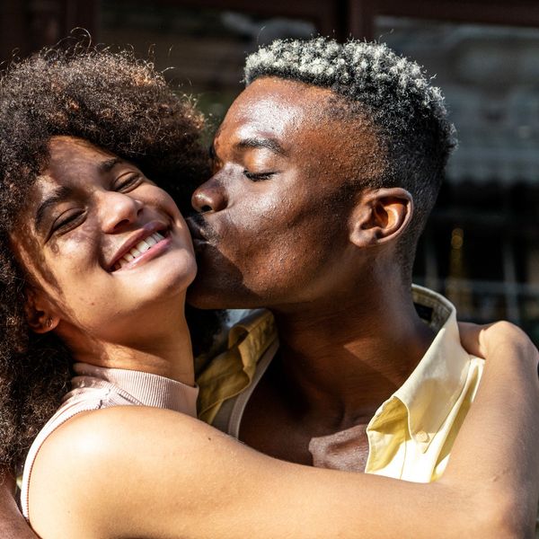 Young-man-kissing-girlfriend-on-the-cheek-outdoors