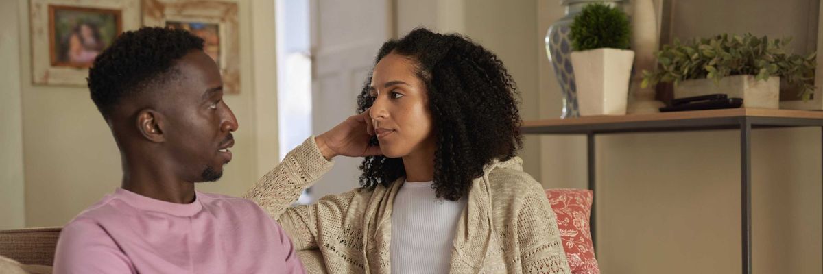 Young multiracial couple having an intimate conversation on their living room sofa, emotional connection and healthy communication
