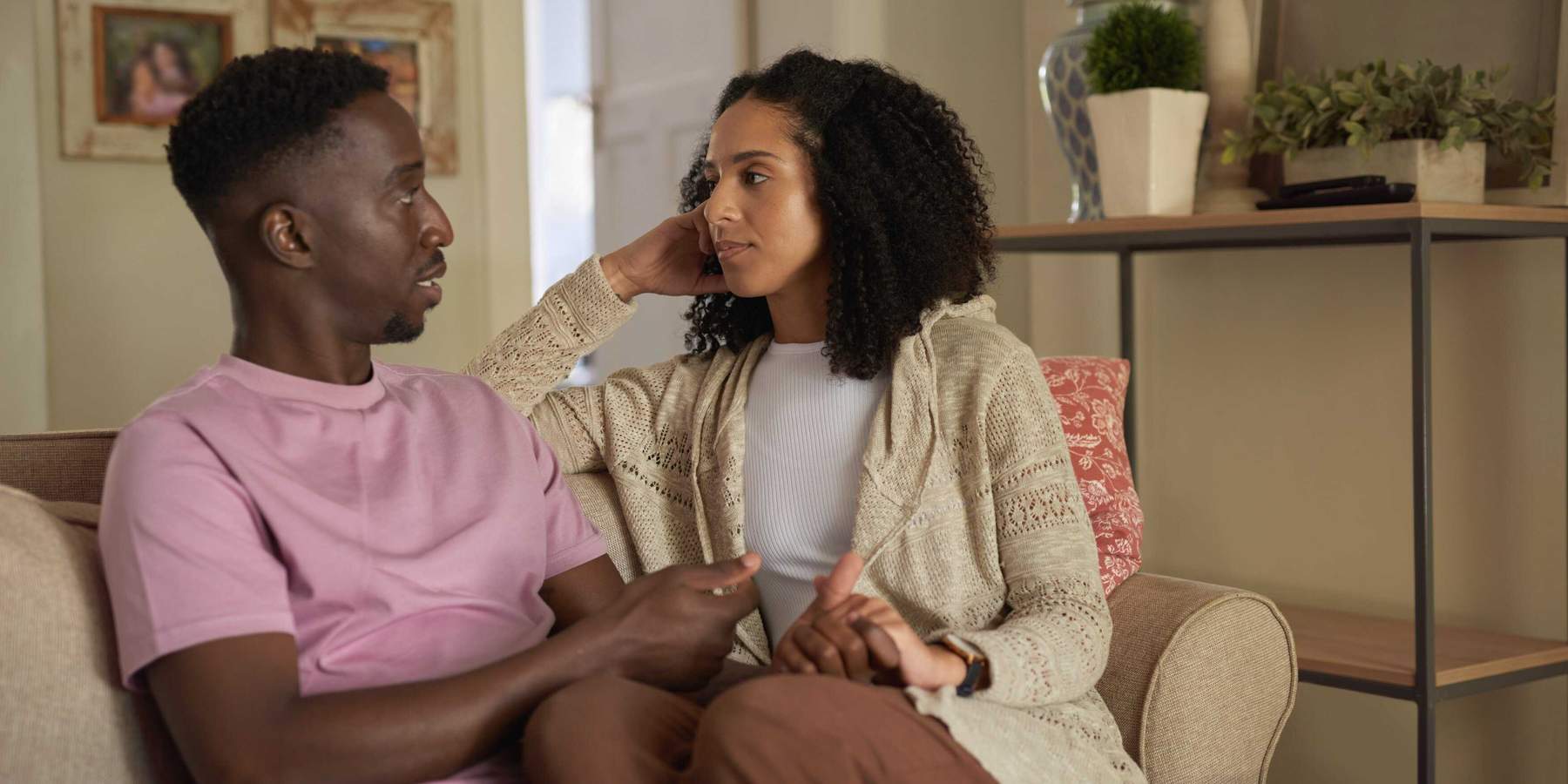 Young multiracial couple having an intimate conversation on their living room sofa, emotional connection and healthy communication