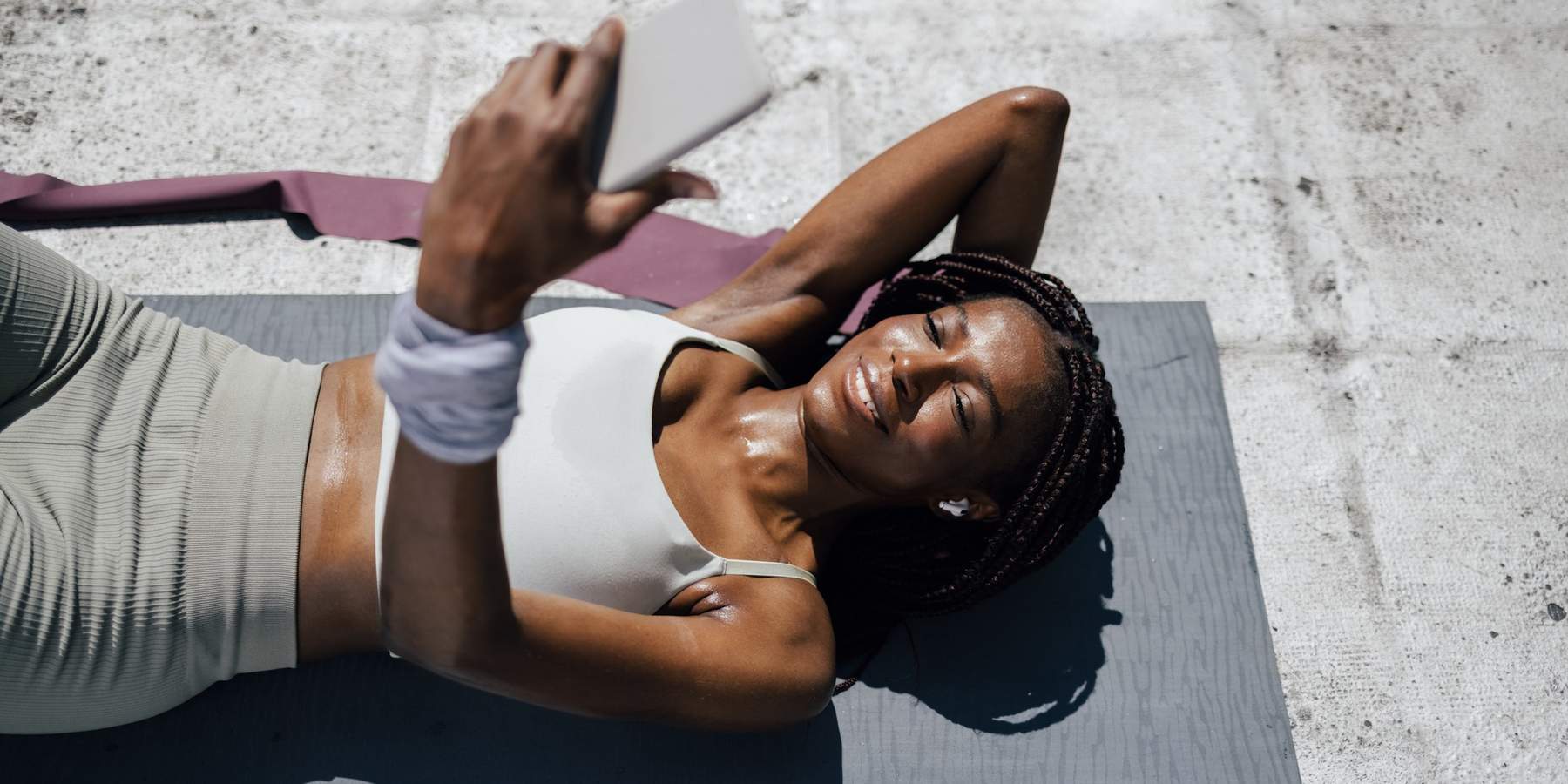 Young-woman-checking-her-phone-after-resting-after-exercising-outside-on-a-mat